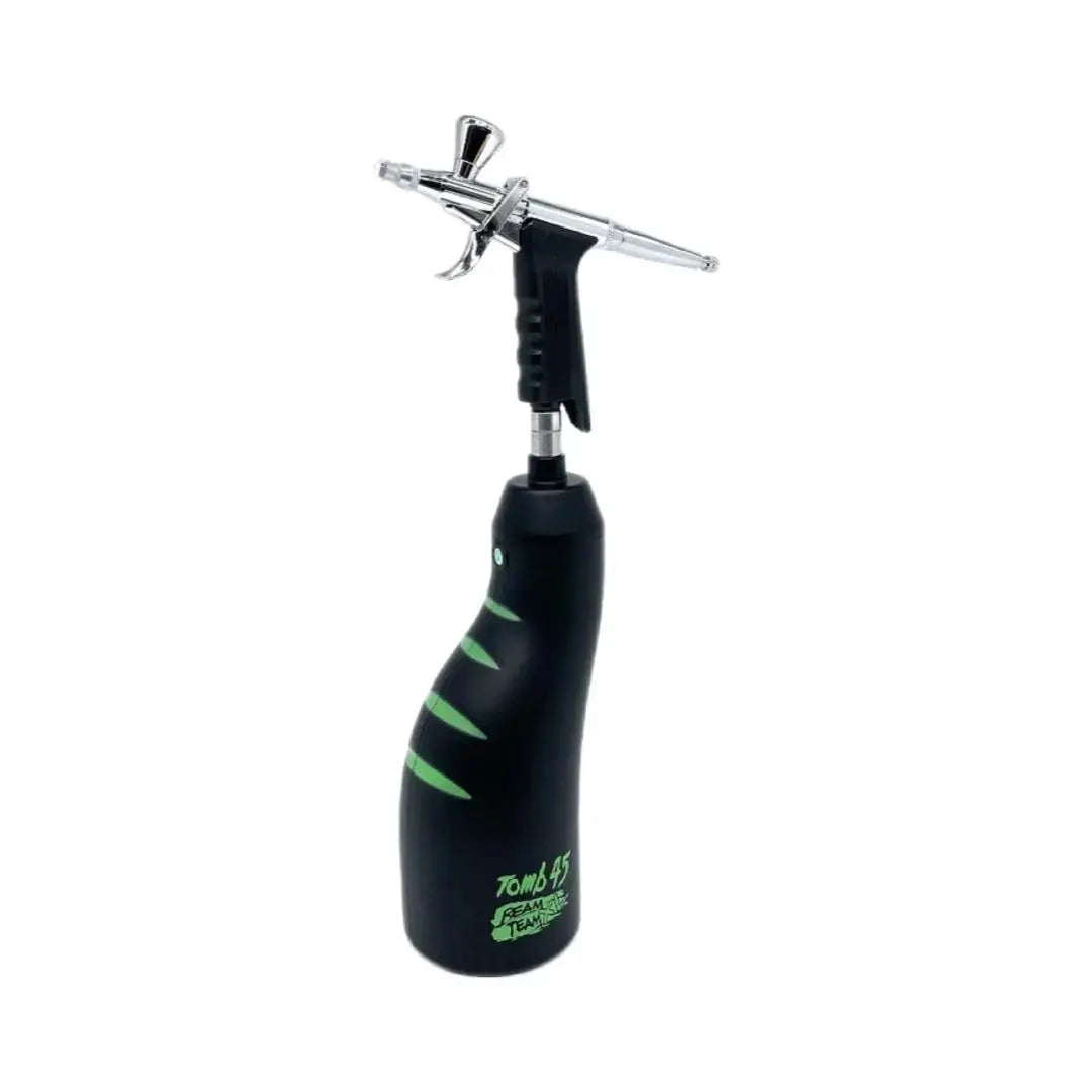 Tomb45 BeamTeam XL cordless airbrush compressor in black with green stripes and a chrome trigger airbrush on a white background